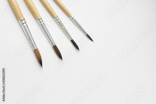 Several paintbrushes on a white paper background