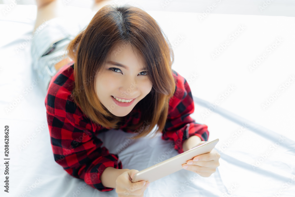 Portrait charming beautiful woman. Attractive beautiful woman is playing tablet on bed in the morning. Attractive beautiful girl gets happiness with smiley face. Asian woman feels relaxing. copy space Portrait charming beautiful woman. Attractive beautiful woman is playing tablet on bed in the morning. Attractive beautiful girl gets happiness with smiley face. Asian woman feels relaxing. copy space