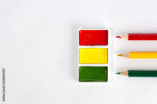 Red Yellow and Green solid watercolor pans and sharp colored pencils on white background with copy space photo