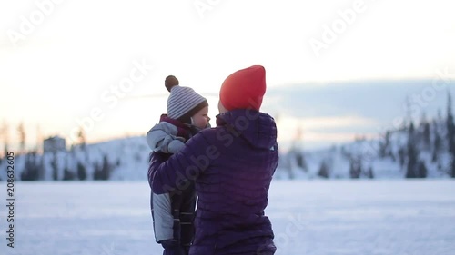 Young mother and little toddler boy having fun with snow outdoors on beautiful winter day, slow motion