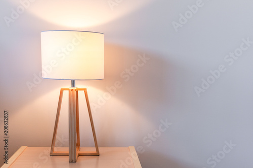 Modern bedroom lamp lit against white wall with copy space