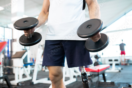Close-up of disabled man standing with dumbbells