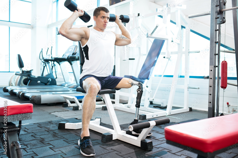 Young disabled man keeps himself in shape in gym Young disabled man keeps himself in shape in gym