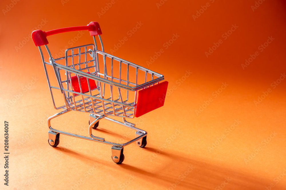 Close up shopping trolley on orange background with copy space Close up shopping trolley on orange background with copy space