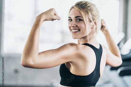 strong and healthy woman pround with her body muscle after workout in gym fitness center