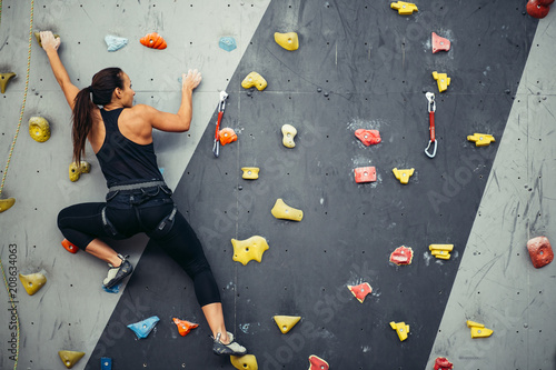 Active sporty woman practicing rock climbing on artificial rock in climbing s. Extreme sports and bouldering concept.