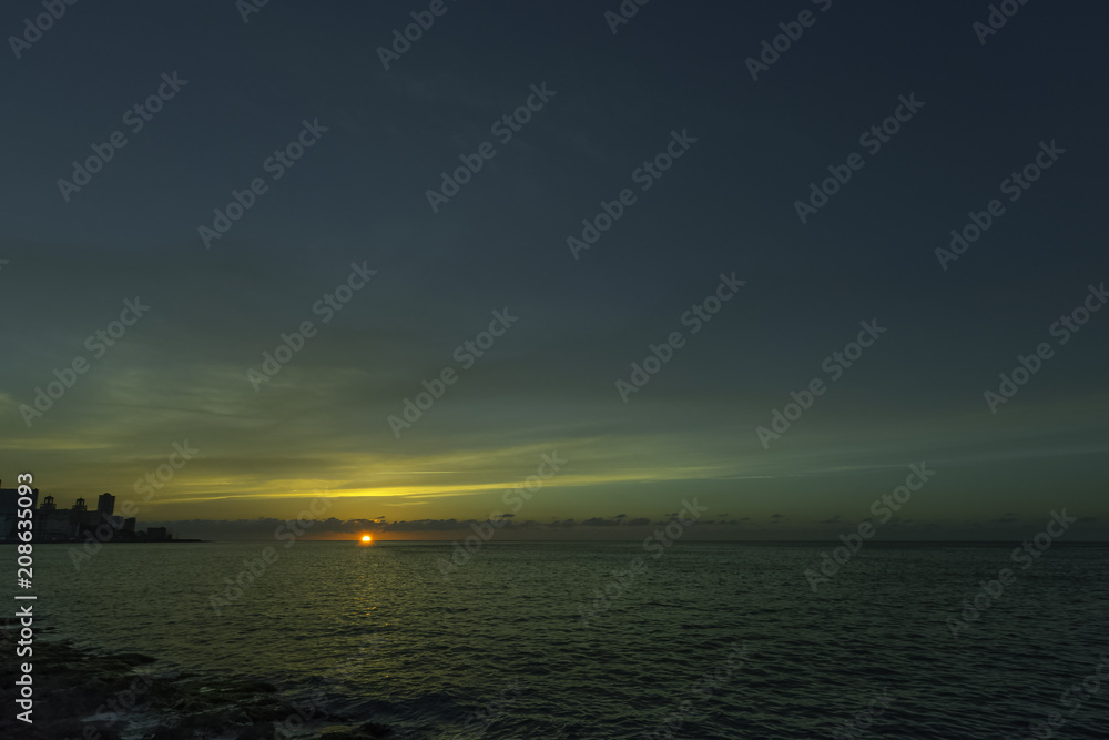 Sunset over Malecon and Atlantic Ocean with residential building in background - Havana, Cuba Sunset over Malecon and Atlantic Ocean with residential building in background - Havana, Cuba