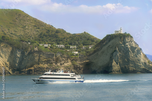 Beautiful view on fast boat from Napoli to Ischia from ferry cruise board. Boat backgrounded by coast and lighthouse on trip to island. Travelling on ship.