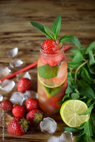 Lemonade with strawberry  lime  ice cubes and mint in a glass bottle