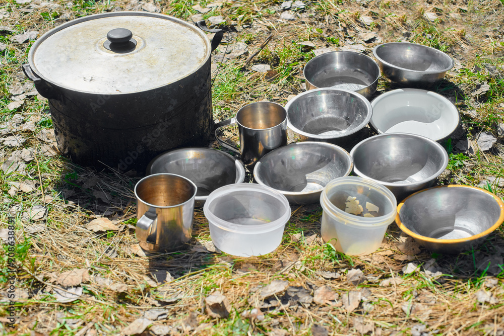 Clousep of cauldron and plates for soup standing on grass in forest Clousep of cauldron and plates for soup standing on grass in forest