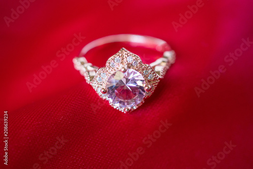 Jewelry luxury pink gold ring with sapphire gemstone on red fabric texture background