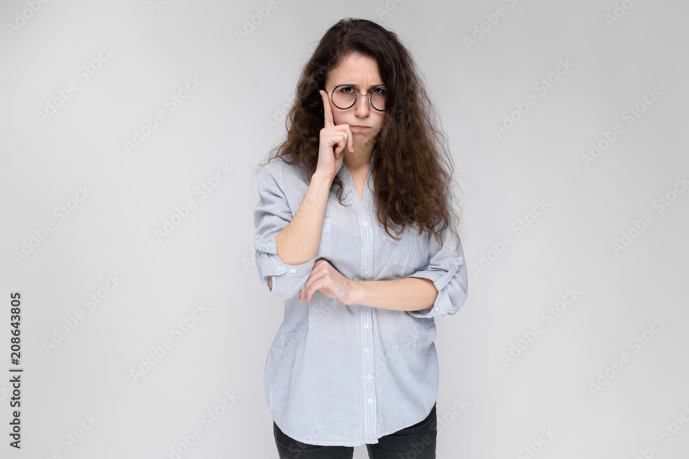 Young brunette girl with glasses. The girl put a finger to her cheek. Young brunette girl with glasses. The girl put a finger to her cheek.