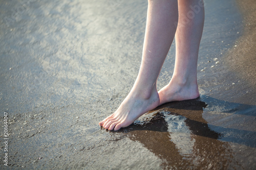 Closeup of a female's bare feet walking at a beach. Concept of the travel, vacation