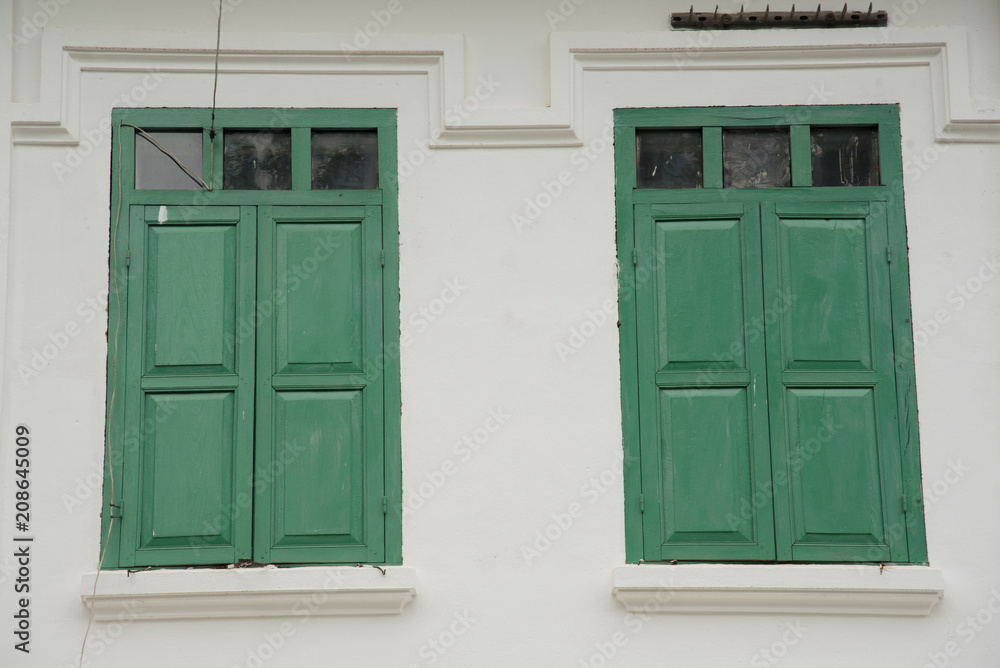 Obraz premium Two green windows on a white building