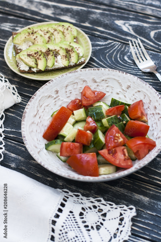 A healthy salad of fresh tomatoes and vegetables and a homemade soft cheese sandwich, avocados and seasoning on toast of hard wheat. A healthy breakfast. A healthy salad of fresh tomatoes and vegetables and a homemade soft cheese sandwich, avocados and seasoning on toast of hard wheat. A healthy breakfast.