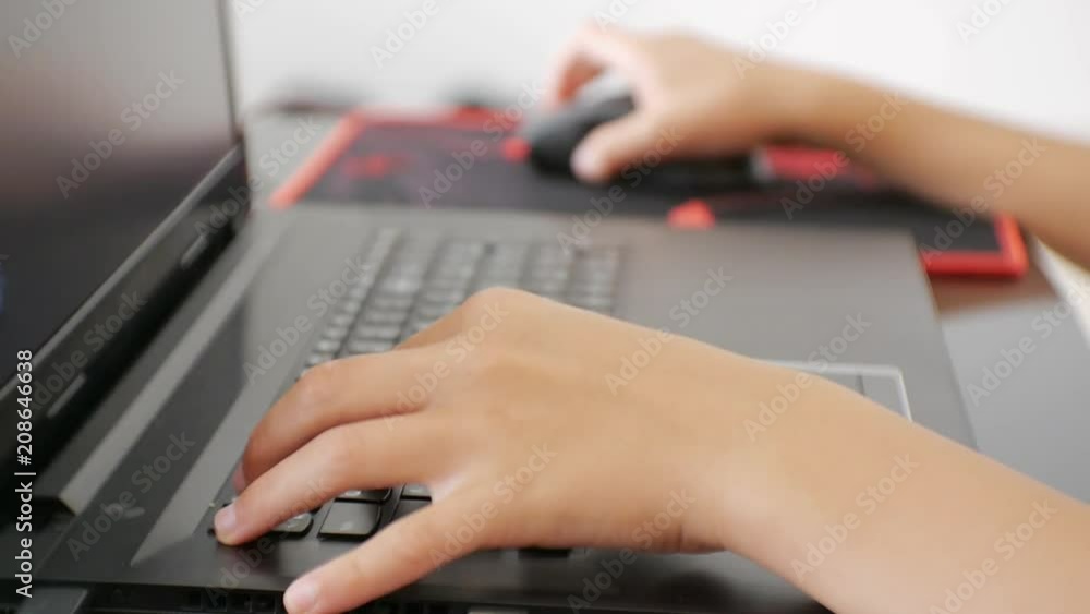 Teenager using laptop. Close-up of teen hands pressing the notebook keyboard Teenager using laptop. Close-up of teen hands pressing the notebook keyboard