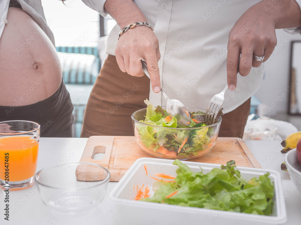 Pregnancy healthy food and people concept.future dad and mom eating healthy salad and take care together.