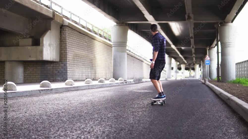 A man riding a skateboard on the asphalt on the background of the overpass A man riding a skateboard on the asphalt on the background of the overpass