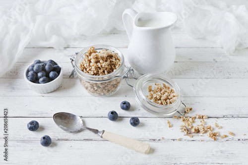 Oat flakes and fresh blueberries with milk. Delicious, healthy and useful breakfast on white wooden table background. Top view, close up.