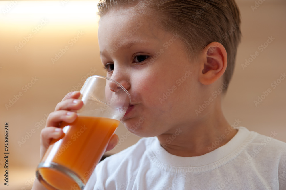 Close-up of charming little boy drinking freshly squeezed orange juice from glass goblet. Concept of healthy eating Close-up of charming little boy drinking freshly squeezed orange juice from glass goblet. Concept of healthy eating