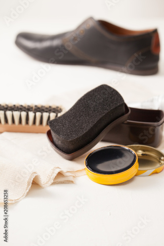 Shoe cream and a brush with a rag to care on a white background.