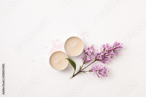 Salt, candles and a sprig of lilac for aromatherapy on a white
