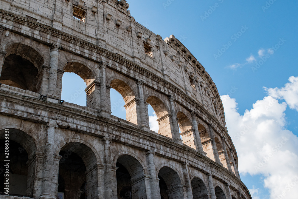 Detail of the Colosseum, columns and arches in Rome backed by a beautiful sky.