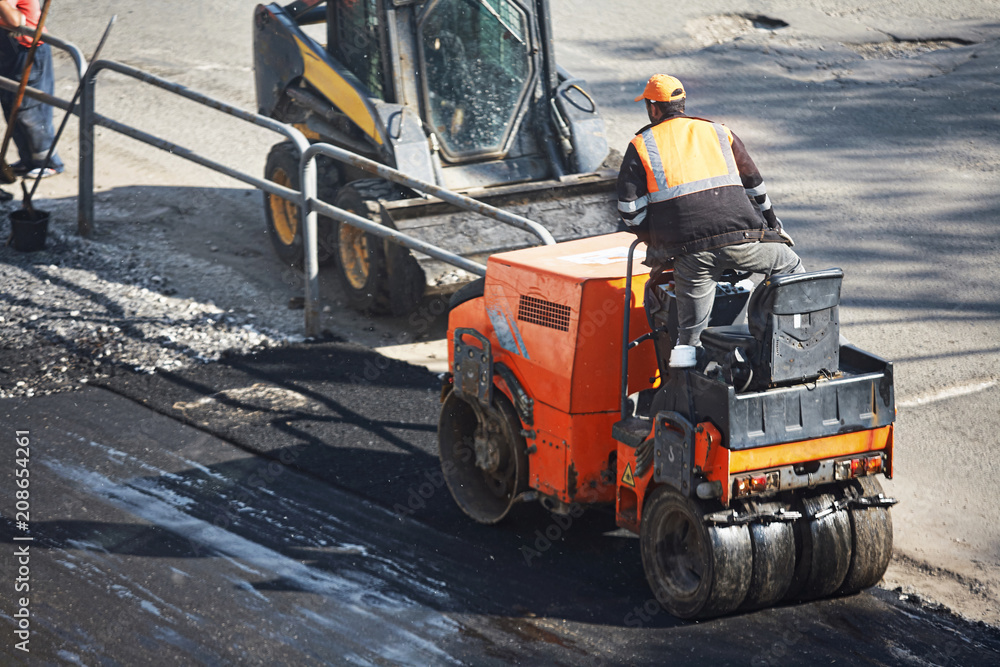 A small machine for laying a new asphalt. Asphalt paving. A small machine for laying a new asphalt. Asphalt paving.