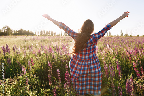 Healthy freedom woman relaxing with open arms in spring sunset field outdoor. People freedom concept