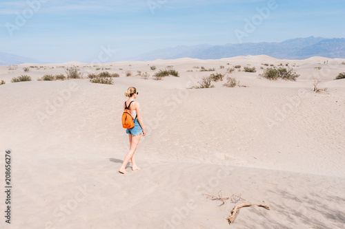 Girl with backpack walks on the desert in the lowest point on earth in Death valley, USA, West Coast