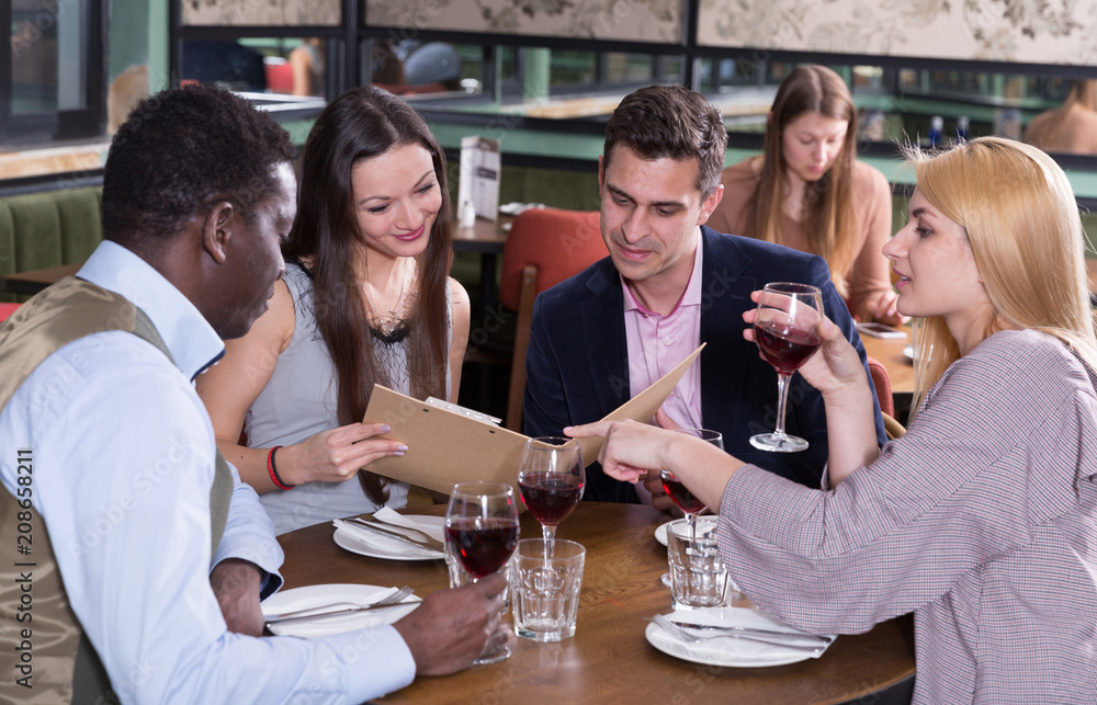 Happy people discussing restaurant menu