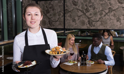 Smiling waitress with ordered dishes