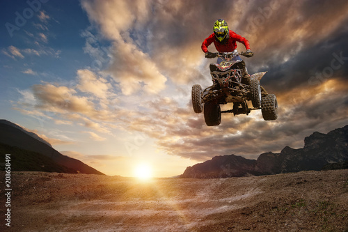Man on atv jump on the trail during sunset.