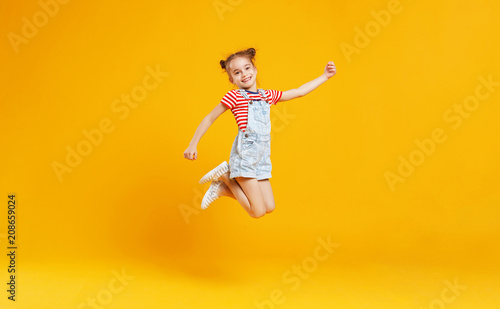 Obraz na plátne funny child girl jumping on colored yellow background