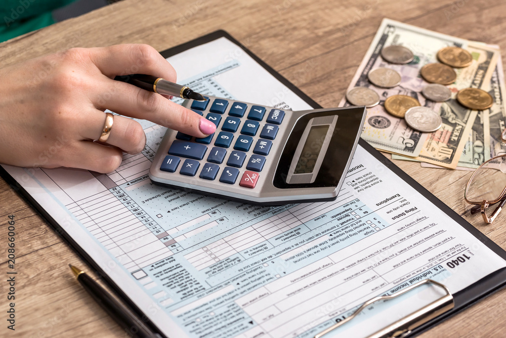 woman filling tax form with money and calculator woman filling tax form with money and calculator