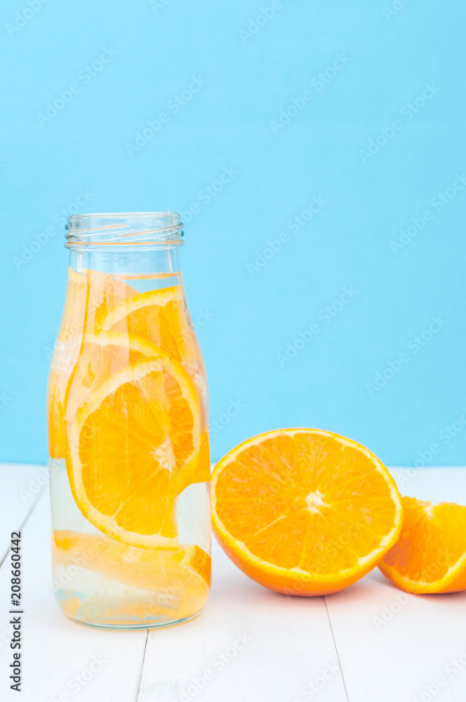 Front view of glass bottle with a detox orange water Front view of glass bottle with a detox orange water