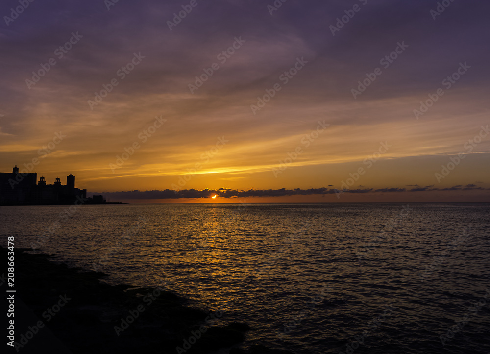 Sunset over Malecon and Atlantic Ocean with residential building in background - Havana, Cuba 