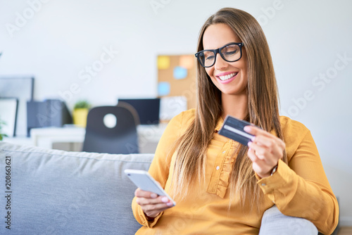 Young woman using credit card and smartphone to pay for shopping online