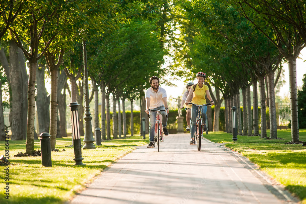 Fototapeta premium Young cyclists riding in park. Tourist on summer holiday. Active students on weekend.