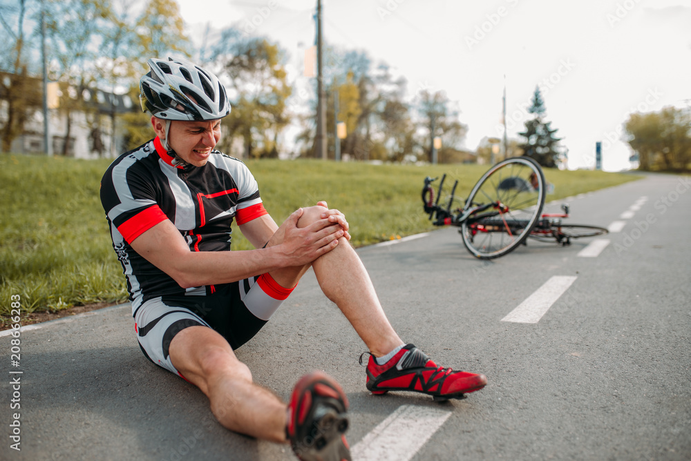 Obraz premium Mężczyzna rowerzysta spadł z roweru i uderzył się w kolano