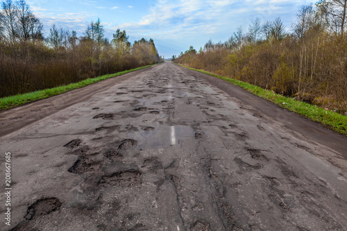 Dangerous potholes in the asphalt rural road. Road damage photo