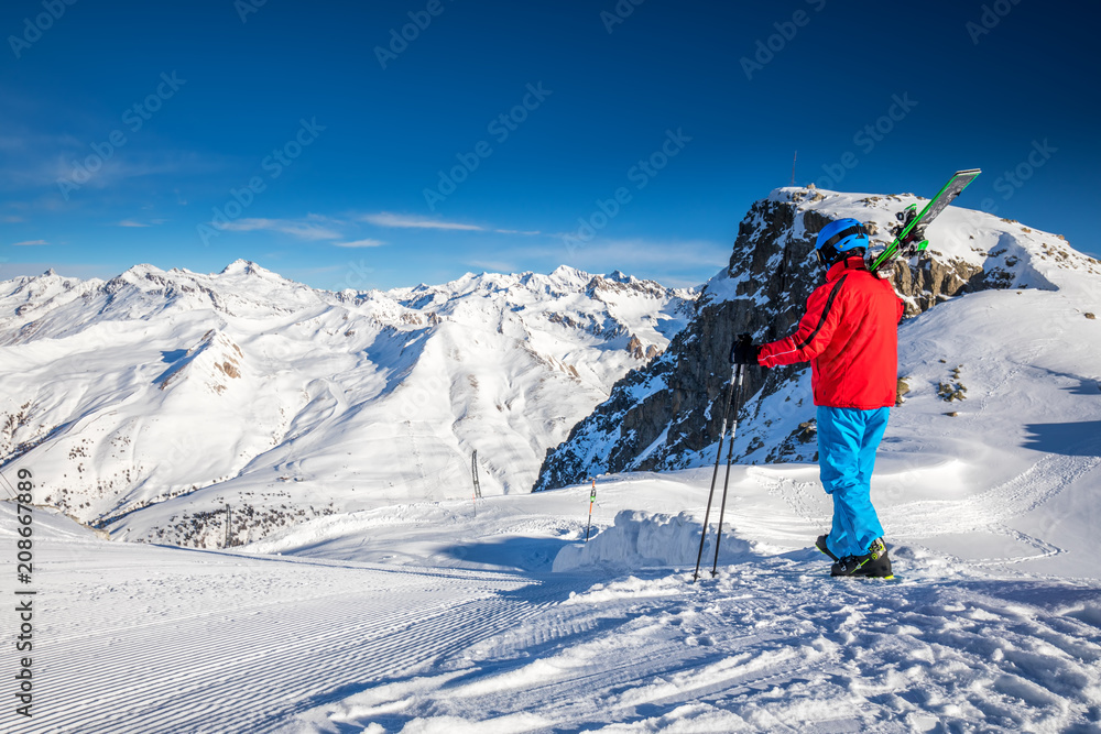 Young happy skier sitting on the top of mountains and enjoying view of Rhaetian Alps, Tonale pass, Italy, Europe