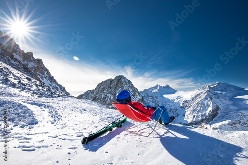 Young happtyattractive skier sitting on the top of mountains enjoying the view from Presena Glacier, Tonale, Italy