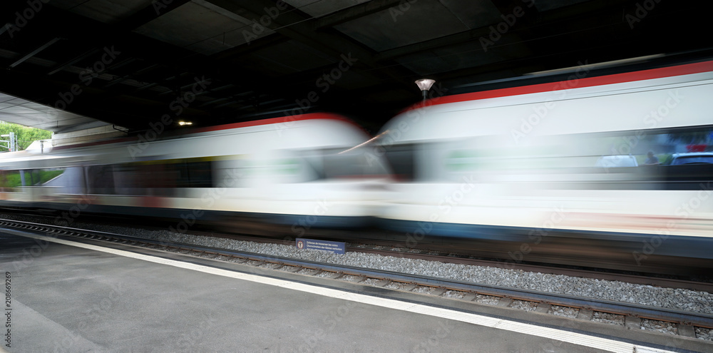 Train speeding through a swiss station captured as a motion blur