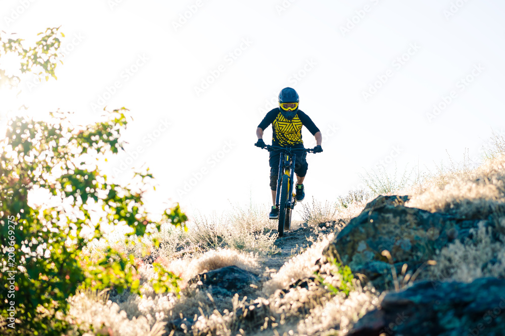 Cyclist Riding the Mountain Bike on the Summer Rocky Trail at the Evening. Extreme Sport and Enduro Cycling Concept. Cyclist Riding the Mountain Bike on the Summer Rocky Trail at the Evening. Extreme Sport and Enduro Cycling Concept.