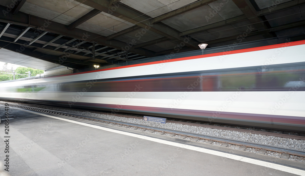 Train speeding through a swiss station captured as a motion blur