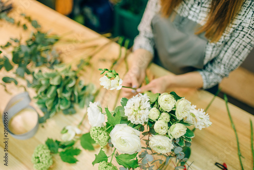 Female florist with pruner in hands makes bouquet