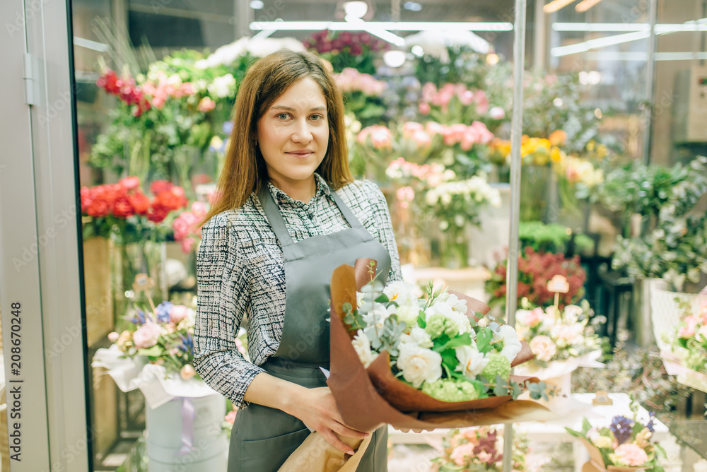 Florist in apron with fresh bouquet in flower shop