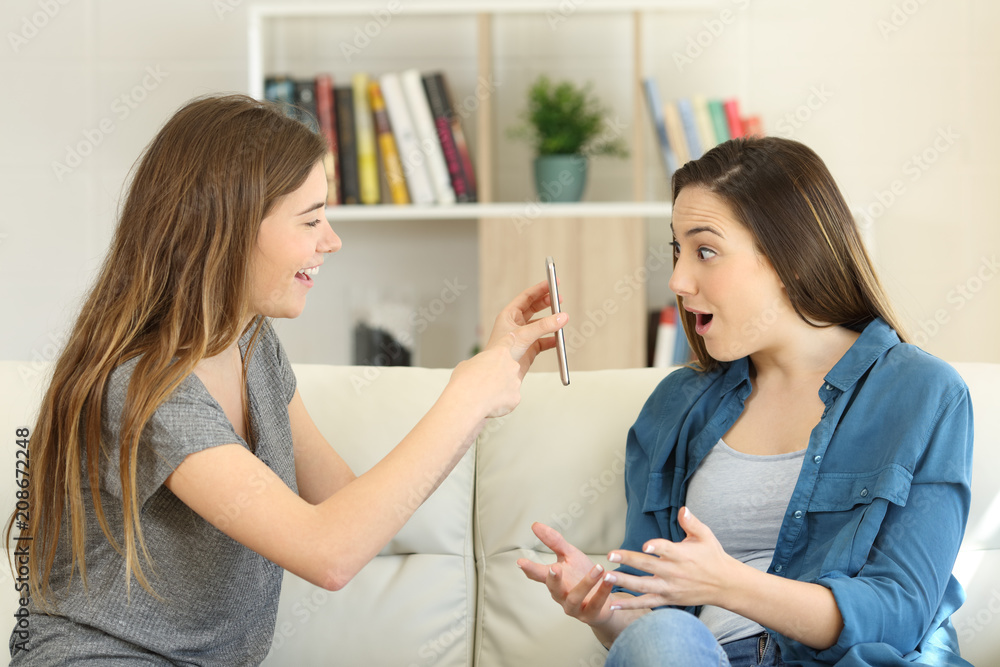 Girl showing smart phone content to an amazed friend Girl showing smart phone content to an amazed friend