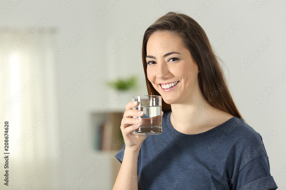 Happy girl holding a transparent glass of water Happy girl holding a transparent glass of water
